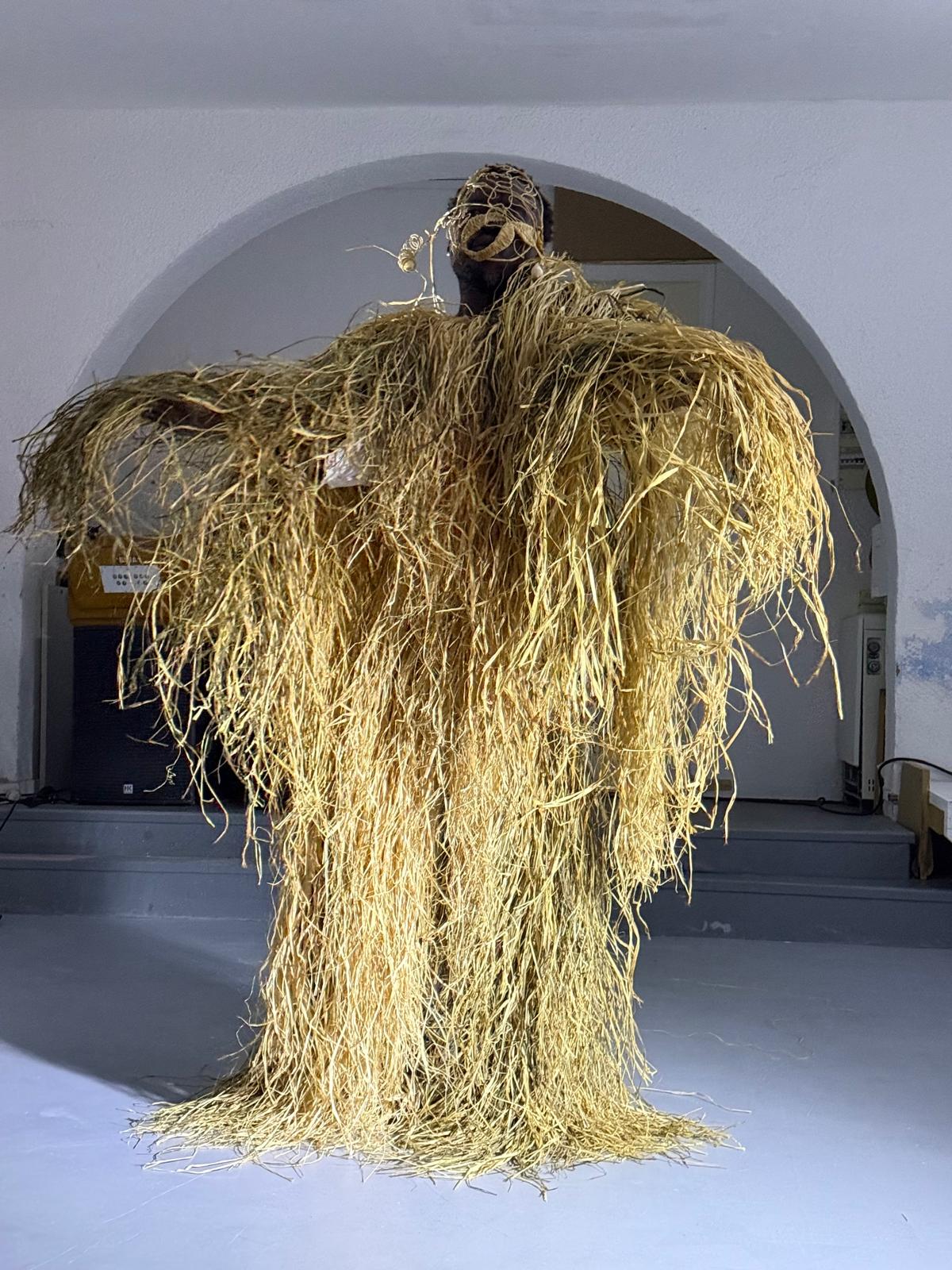 Interprète portant un masque et une ample tenue de raphia